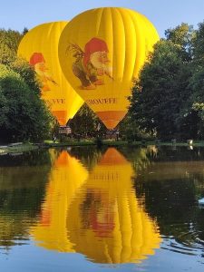 Deux montgolfières avec le logo Chouffe reflétées dans un étang, organisées par la société Montgolfière Ardenne pour des vols en montgolfière dans les Ardennes
