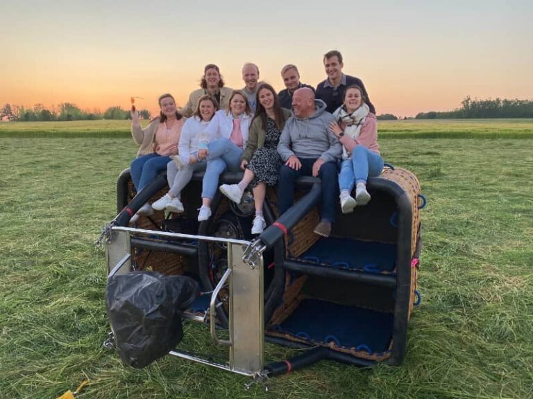 Famille assise sur la nacelle d’une montgolfière au coucher du soleil après un vol en montgolfière avec Montgolfière Ardenne